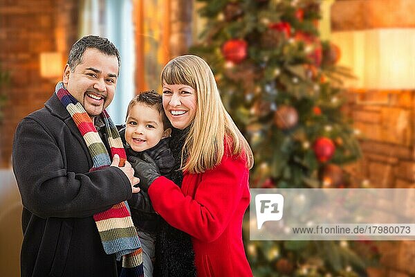 Junges gemischtrassiges Familienporträt vor einem Weihnachtsbaum in einem Haus