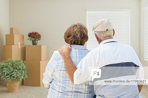 Älteres Ehepaar vor leerem Zimmer mit gepackten Umzugskartons und Topfpflanzen