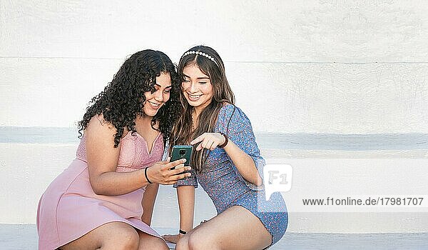 Zwei Mädchen zeigen auf ihr Handy  Mädchen zeigt ihr Smartphone ihrer Freundin  Mädchen überprüft ihr Handy mit ihrer Freundin