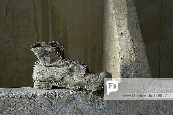 Arbeitsschuh aus Leder auf Mauer  verrottete Schuhe am Boden  verrotteter Schuh  Schuhwrack  vergammelter Treter  ausgelatschter Schuh  abgetragener Schuh