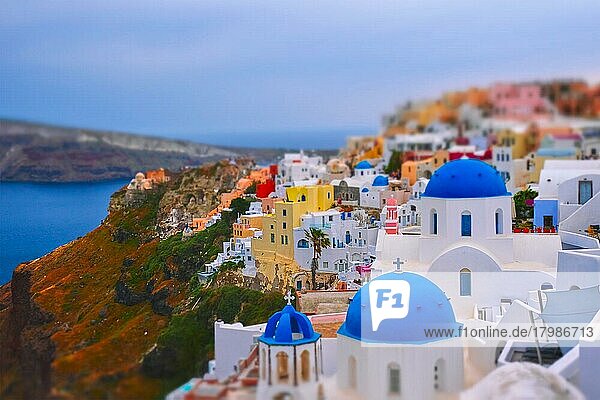 Famous greek iconic selfie spot tourist destination Oia village with traditional white houses and church in Santorini island on sunset in twilight  Greece. Toy camera tilt shift miniature effect