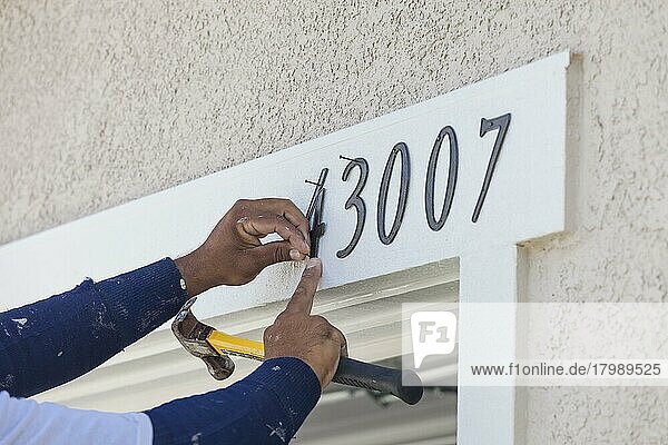 Ein Malerbetrieb nagelt Adressnummern auf die Hausfassade