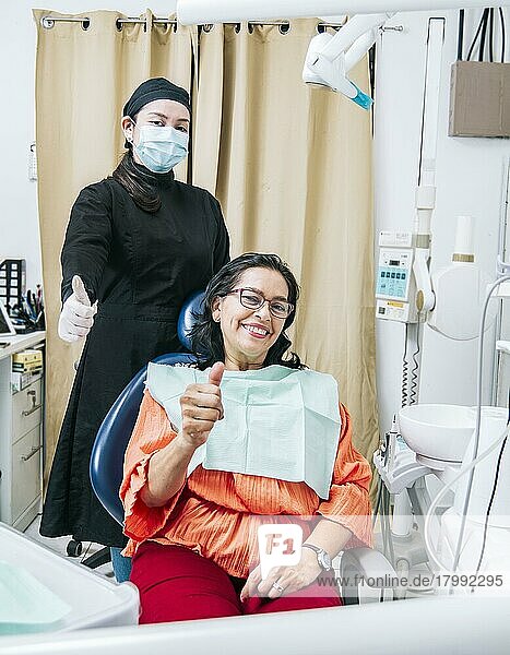 Dentist with thumb up patient in office  Woman shows thumb up sitting in dentist office  Dentist and satisfied patient with thumb up