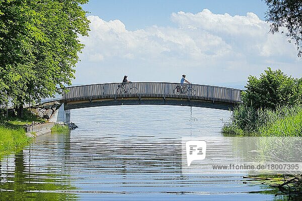 Zwei Fahrradfahrer überqueren die Brücke über den Bach Aach bei der Mündung in den Bodensee  Arbon im Thurgau  Schweiz  Europa
