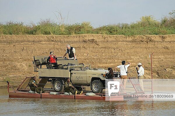 Safari-Fahrzeug und Touristen  die den Fluss auf einem Ponton überqueren  River Luangwa  South Luangwa N.P.  Sambia  Juni  Afrika