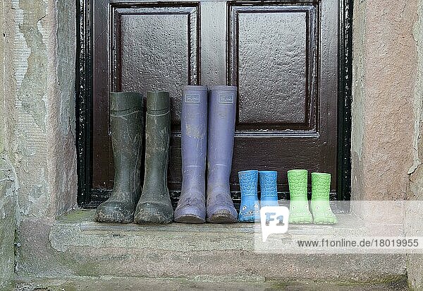 Vier Paar Gummistiefel  zwei Paar Kinderstiefel  ein Paar Damen- und ein Paar Herrenstiefel  vor der Tür des Bauernhauses  Whitewell  Lancashire  England  Dezember