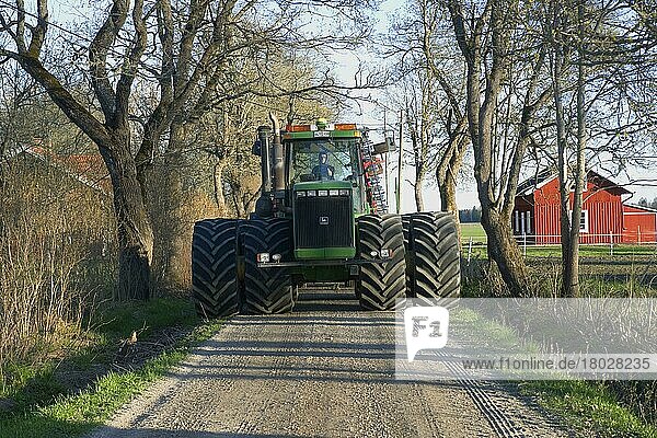 John Deere 9400 Traktor mit zwei Rädern  fährt auf kleiner Straße auf dem Weg zu den Feldern  Uppland  Schweden  Mai  Europa