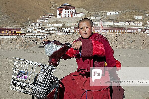 Junger Mönch fährt Roller vor dem tibetischen Kloster Sershu Dzong im Dorf Sershu  Serxu  Provinz Sichuan  China  Asien