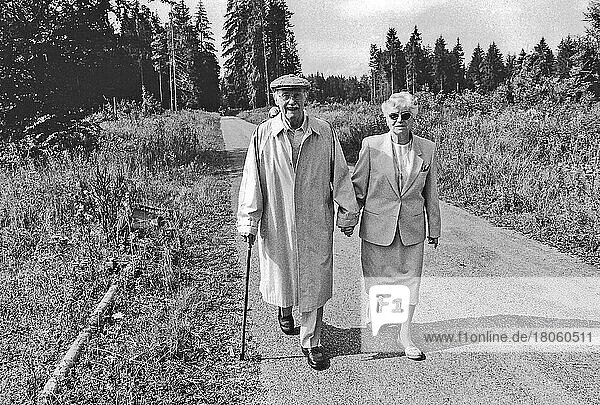 Altes Ehepaar läuft Hand in Hand auf Waldweg  Grünwald  Bayern  Deutschland  Europa