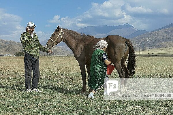 Kasachischer Mann mit Handy und kasachische Frau beim Melken einer Stute  Gabagly-Nationalpark  Shymkent  Südregion  Kasachstan  Zentralasien  Nur für redaktionellen Gebrauch  Asien