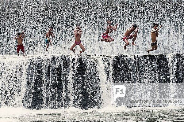 Jungen springen in einen Wasserfall und haben Spaß  Bali  Indonesien  Asien