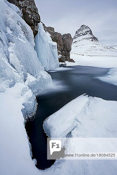 Der Berg Kirkjufell und der gefrorene Wasserfall Kirkjufellsfoss auf der Halbinsel Snæfellsnes im Schnee im Winter  Island  Europa