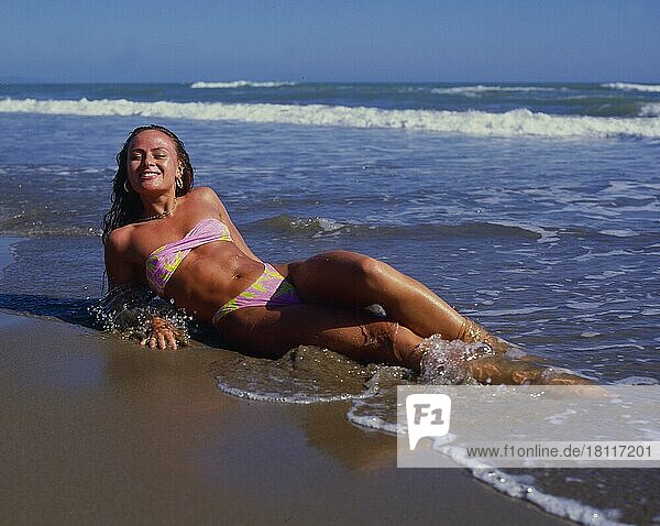 Junge Frau im Wasser liegend  Sandstrand