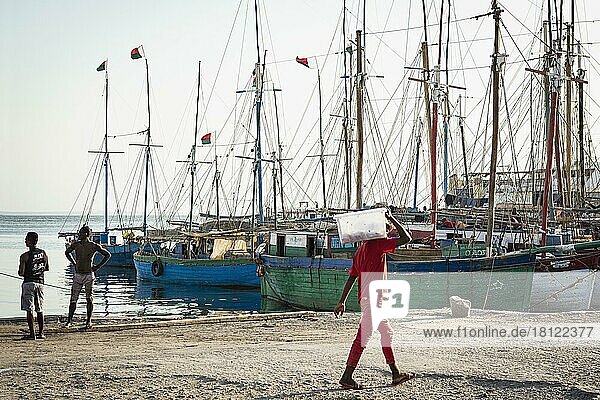 Mann in roter Kleidung trägt Sack  hinten Fischerboote  alter Hafen  Mahajanga  Madagaskar  Afrika