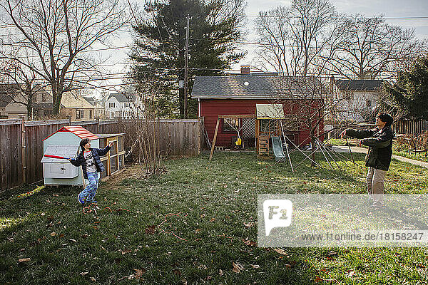 A father and son play baseball together in backyard in autumn