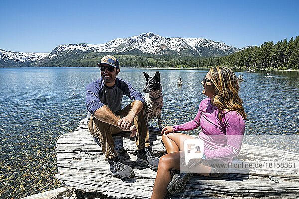 A couple relaxes with their dog on the shoreline of Fallen Leaf Lake.