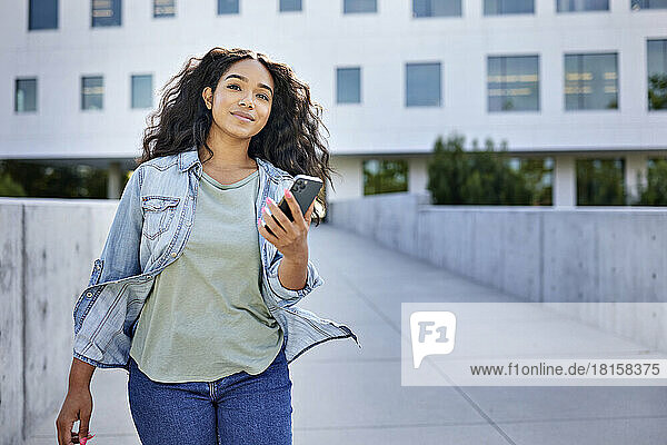 Frau mit Smartphone vor einem Gebäude