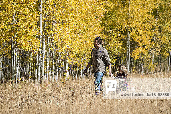 A father and his daughter hike through a grove of Aspen trees.