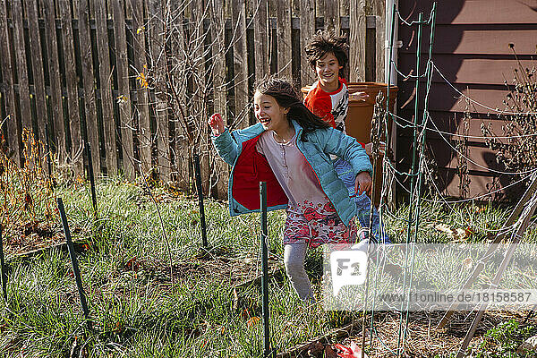 Zwei glückliche Kinder spielen im Sonnenschein im Hinterhof Garten