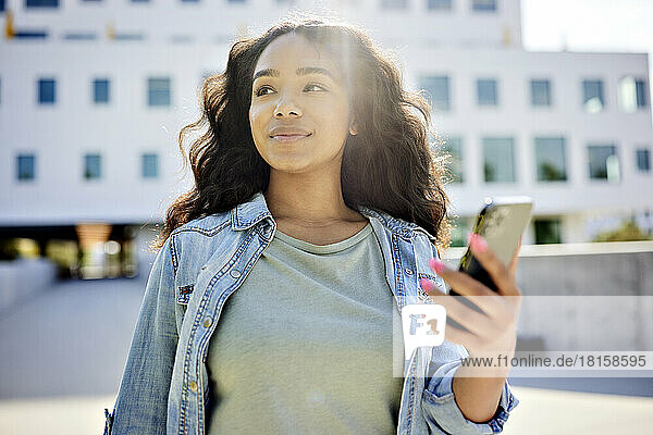Woman looking away holding smart phone