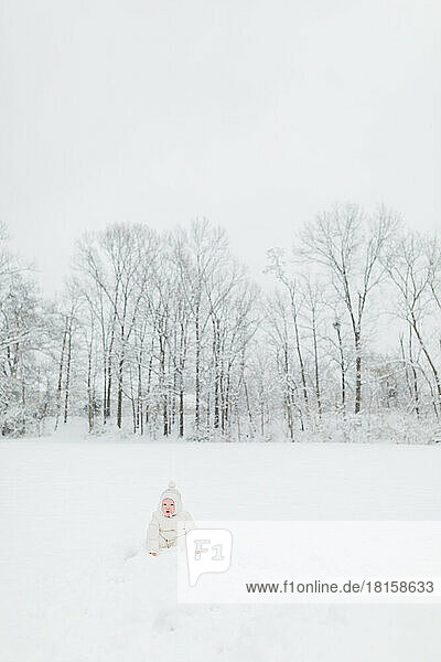 Ein einjähriges Baby sitzt auf einem verschneiten Feld in Maryland im Winter.