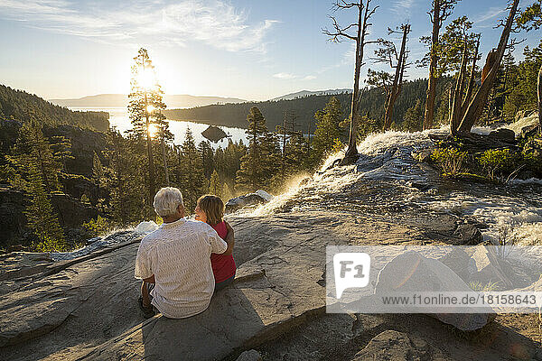 A man and a woman enjoy the sunrise over Emerald Bay.