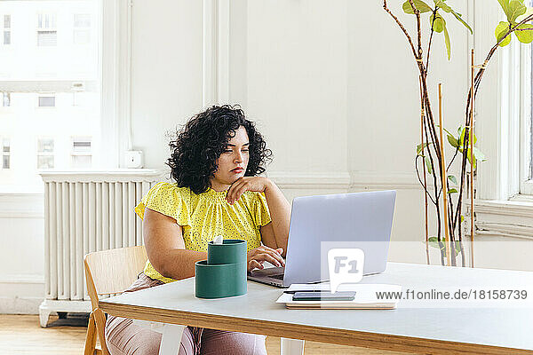 Junge Geschäftsfrau mit Laptop auf dem Schreibtisch im Bürostudio