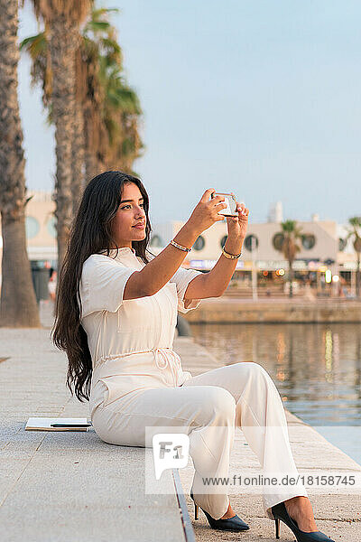 Latina businesswoman takes a picture with her phone in a harbor