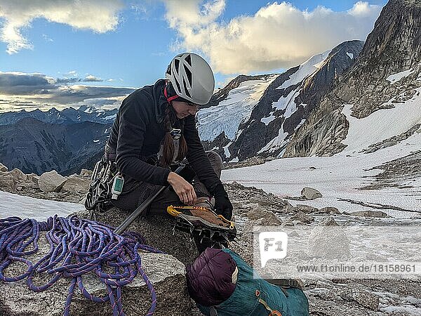 Woman Attaches Crampons In Mountains