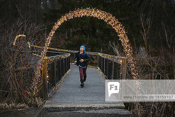 Ein Junge läuft durch eine beleuchtete Brücke in der Abenddämmerung im Winter