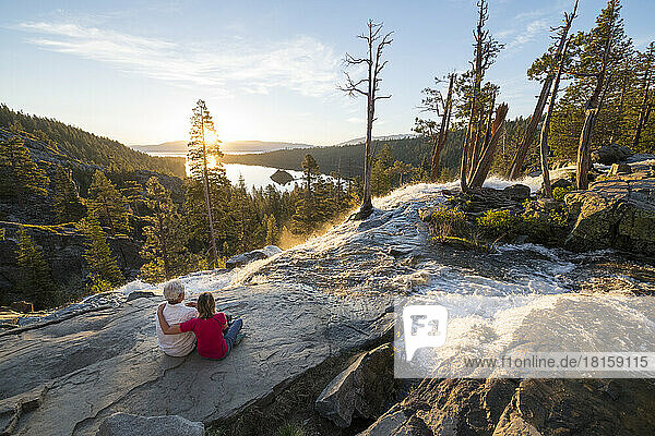 A man and a woman relax at the top of Eagle Falls at sunrise.