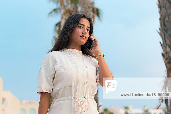 Business junge lateinische Frau spricht durch sein Mobiltelefon draußen