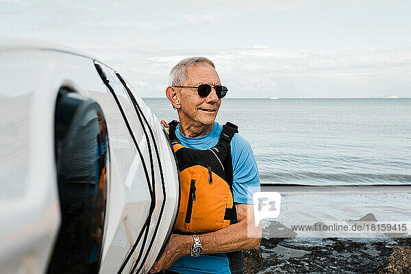 Mann im Ruhestand beim Kajakfahren am Strand an einem sonnigen Tag