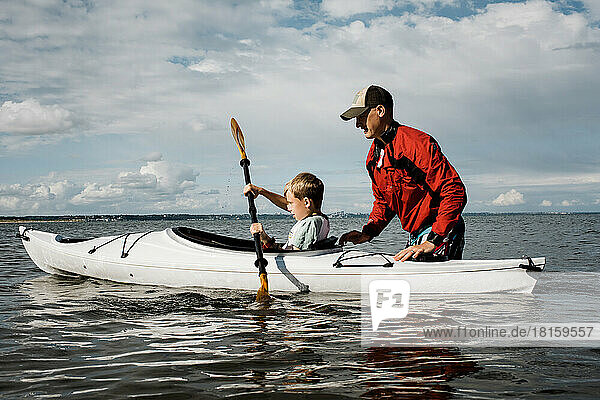 father teaching his son to Kayak in the sea on a sunny day