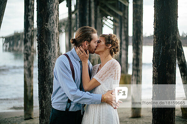 Ein frisch verheiratetes Paar küsst sich am Strand in den Redwoods  Kalifornien