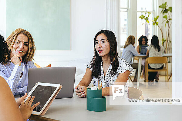 Businesswoman holding ipad discussing strategy with female colleagues