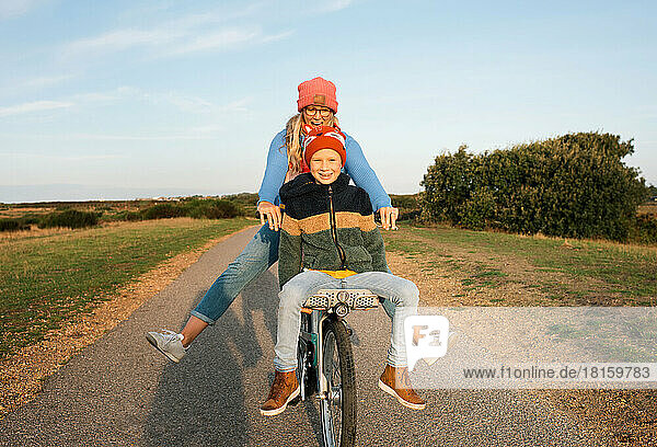 mother and son cycling on a rental bike at the beach at sunrise