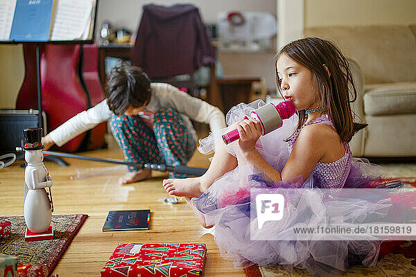 Kleines Mädchen im Kostüm und Bruder spielen mit Weihnachtsgeschenken