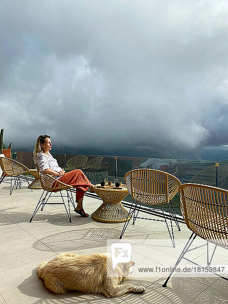 Schöne Frau entspannt auf der Terrasse eines Cafés mit Hund