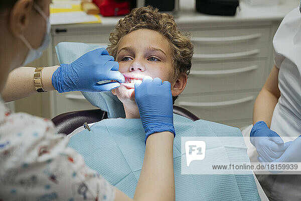 Ein Kieferorthopäde kontrolliert die Zähne und den Biss des Jungen.