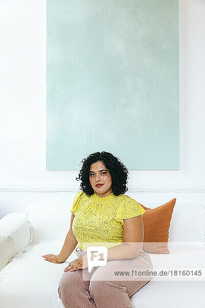 Porträt einer selbstbewussten Geschäftsfrau  die in einem kreativen Büro auf dem Sofa sitzt