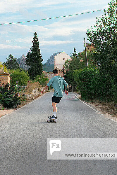 Junger Mann fährt auf einem Skateboard auf einer Straße