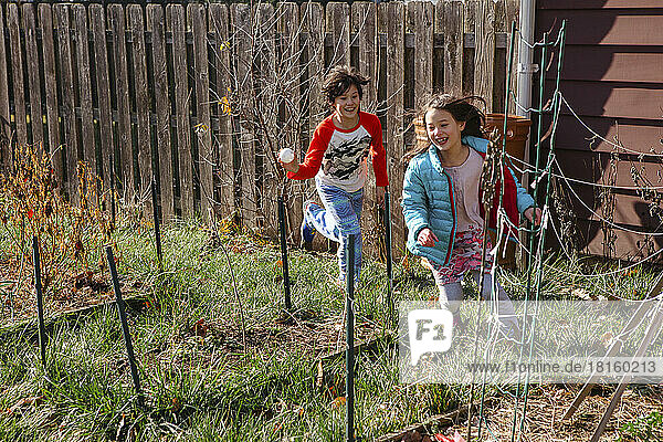 Zwei Kinder spielen Verfolgungsjagd durch den Garten im Frühling