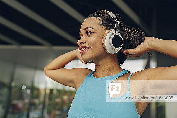 Smiling woman listening to music through wireless headphones