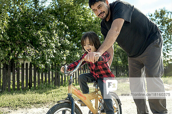 Man pushing son on bicycle