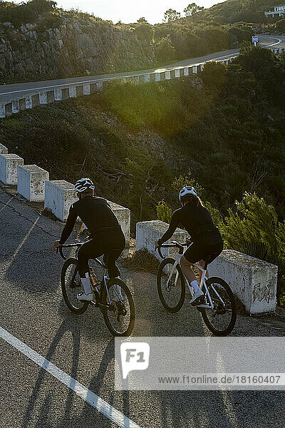 Man and woman cycling together on road  Alicante  Spain