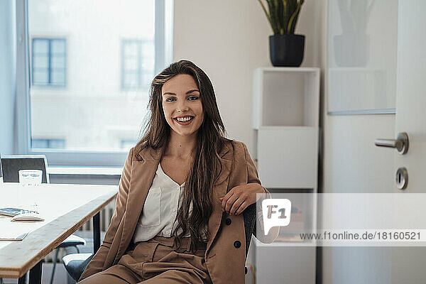 Smiling young woman with long hair sitting in home office