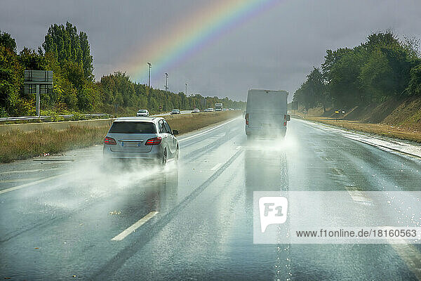 France  Normandy  Rouen  Traffic along wet highway with rainbow arching in background