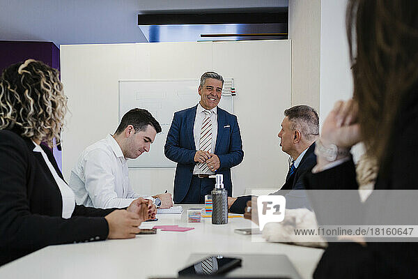 Lächelnder reifer Geschäftsmann diskutiert mit Kollegen bei einem Treffen im Büro