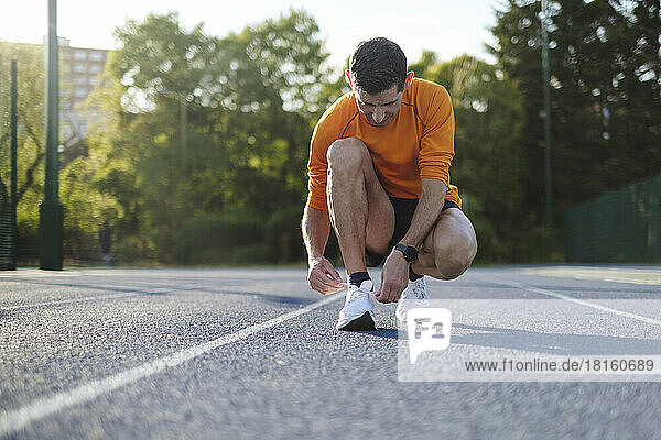 Sportler bindet Schnürsenkel auf der Strecke